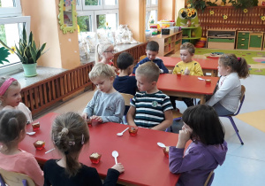 dzieci siedzą przy stolikach, jedzą słodkie deserki