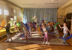 dzieci tańczą trzymając kolorowe chusteczki