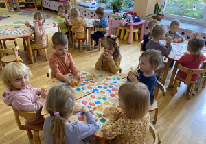dzieci siedzą przy stolikach i jedzą babeczki