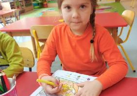 dziewczynka w pomarańczowej koszulce koloruje dynie