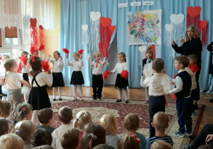 dzieci wykonują taniec, w dłoniach trzymają biało-czerwone pompony