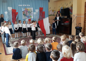 dzieci recytują wiersz, chłopiec trzma w dłoniach flagę Polski