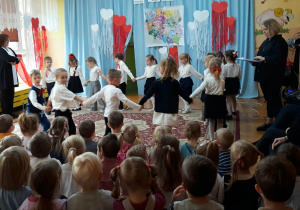 dzieci tańczą na dywanie, trzymając się za ręce tworzą koło