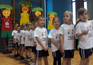 dzieci stoją w rzędzie w strojach gimnastycznych przed rozpoczęciem konkurencji