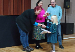 dziewczynka otrzymuje dyplom oraz nagrodę za udział w konkursie