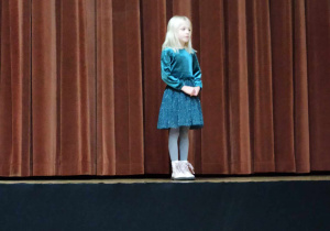 dziewczynka stoi na scenie i recytuje wiersz