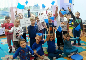 dzieci trzymają w dłoniach niebieskie chorągiewki oraz plakietki z napisami mamy prawo do: życia w rodzinie, do zdrowia i bezpieczeństwa