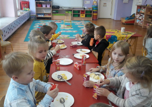 dzieci jedzą przy stole tort z okazji urodzin Jasia