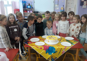 Dzieci składają życzenia Jasiowi, na stole leży tort