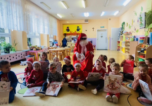 dzieci z Mikołajem pozuja do zdjęcia, w dłoniach trzymają kalendarz adwentowy