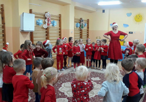 dzieci w czerwonych strojach ustawione w dużym kole tańczą