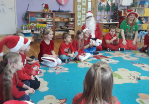 dzieci siedzą na dywanie z Mikołajem i Elfem