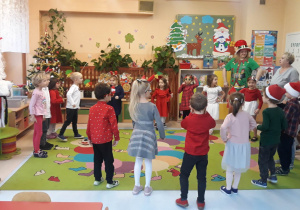 Mikołaj, elf i dzieci tańczą na dywanie