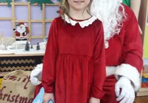 dziewczynka pozuje do zdjęcia z Mikołajem i Elfem