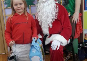 dziewczynka pozuje do zdjęcia z Mikołajem i Elfem