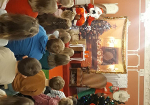 dzieci słuchają opowieści Mikołaja, który siedzi na czerwonym fotelu