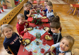 dzieci siedzą przy stole i jedzą wigilijny obiad