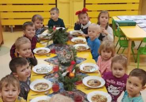 dzieci siedzą przy stole i jedzą obiad